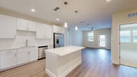 Located at 1023 Gull Ln in Melbourne, FL, this well-appointed 2-bedroom, 3-bathroom residence offers a thoughtfully designed single-floor layout that balances comfort and modern style. The open-concept living area seamlessly connects the kitchen, dining, and living spaces, all finished with light wood-look flooring that creates a warm, cohesive feel. The kitchen is a standout feature, showcasing crisp white cabinetry extending to the ceiling, a large center island with a quartz countertop, subway tile backsplash, and a full suite of stainless steel appliances, including a refrigerator with ice maker, range, microwave, and dishwasher. Pendant lighting above the island adds a modern touch. The living area is bright and open, benefiting from natural light and a ceiling fan. Both bedrooms are carpeted and well-sized, each with ceiling fans. The spacious primary bedroom connects to a generously sized en-suite bathroom featuring a glass-enclosed walk-in shower with large-format tile, a white vanity with quartz countertop, and an illuminated mirror. The secondary bathroom offers a tiled tub-shower combo with equally refined finishes. Three closets, including a walk-in with wire shelving, provide ample storage. A private balcony and in-unit laundry area complete this move-in-ready home.