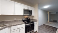 This thoughtfully remodeled 2-bedroom residence offers a clean, modern aesthetic across a well-organized single-floor layout. The updated kitchen is a standout feature, showcasing crisp white shaker-style cabinetry, granite-style countertops, and a full suite of stainless steel appliances including a refrigerator, dishwasher, electric range, and built-in microwave. Wood-look flooring anchors the kitchen and flows into adjacent areas, providing a durable and stylish foundation. The open living area is generously sized, featuring neutral carpet, a sliding glass door that invites natural light, and vertical blinds for privacy. The layout connects the living space seamlessly to the kitchen and hallway, creating an efficient and comfortable flow. The bedrooms are carpeted and well-lit, each featuring multiple windows that bring in ample natural light. The bathrooms have been updated with white vanity cabinetry, brushed nickel hardware, large mirrors, and wood-look flooring. One bathroom includes a tub/shower combo with a grab bar, while the other features a bright vanity with clean, neutral finishes. The overall design presents a move-in ready space with consistent, contemporary upgrades throughout.
