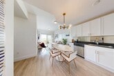 Located at 3800 Crystal Lake Drive in Deerfield Beach, Florida, this single-floor residence offers four bedrooms and two bathrooms within a bright, efficiently designed layout. The open-concept kitchen and living area form the heart of the home, featuring white shaker cabinetry, dark granite countertops, a mirrored tile backsplash, and a full suite of stainless steel appliances. A striking brass-and-globe chandelier anchors the dining area, where a marble-top oval table serves as a focal centerpiece. Light wood-tone flooring flows continuously throughout, enhancing the airy, cohesive feel of the space. The living room is bathed in natural light from sliding glass doors that open to an outdoor balcony, offering scenic views of the surrounding landscape. A wall-mounted entertainment unit provides a clean, modern aesthetic. The spacious primary bedroom includes a wall-mounted TV panel and connects seamlessly to the overall design language of the home. Additional bedrooms are bright and well-proportioned, each featuring large windows with views to the outdoors. The bathrooms are finished with large-format grey tile surrounds and clean, contemporary fixtures. A connecting hallway ties all rooms together in a functional and streamlined floor plan.