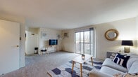 Located at 225 Orville St in Fairborn, Ohio, this single-floor residence offers a well-organized layout designed for comfortable everyday living. The bright living room is finished with plush carpeting and features a wall-mounted air conditioning unit and large sliding glass doors that open onto a private balcony, filling the space with natural light and providing pleasant outdoor views. The kitchen is equipped with white cabinetry, a range, dishwasher, refrigerator, and a double sink, all complemented by warm hardwood-style flooring. An adjoining dining area offers room for a full table, making it well-suited for meals and entertaining. The residence includes two carpeted bedrooms, each with windows that bring in natural light. One bedroom features a walk-in closet with built-in shelving, while the second includes a sliding-door closet. The bathroom is appointed with a vanity, lighted mirror cabinet, and a shower/tub combination. A dedicated laundry room houses a full-size washer and dryer, adding everyday convenience. The overall layout is practical and cohesive, with a neutral color palette throughout that creates a clean and inviting atmosphere.