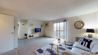 Located at 225 Orville St in Fairborn, Ohio, this single-floor residence offers a well-organized layout designed for comfortable everyday living. The bright living room is finished with plush carpeting and features a wall-mounted air conditioning unit and large sliding glass doors that open onto a private balcony, filling the space with natural light and providing pleasant outdoor views. The kitchen is equipped with white cabinetry, a range, dishwasher, refrigerator, and a double sink, all complemented by warm hardwood-style flooring. An adjoining dining area offers room for a full table, making it well-suited for meals and entertaining. The residence includes two carpeted bedrooms, each with windows that bring in natural light. One bedroom features a walk-in closet with built-in shelving, while the second includes a sliding-door closet. The bathroom is appointed with a vanity, lighted mirror cabinet, and a shower/tub combination. A dedicated laundry room houses a full-size washer and dryer, adding everyday convenience. The overall layout is practical and cohesive, with a neutral color palette throughout that creates a clean and inviting atmosphere.