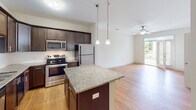 This single-floor residence at 1109 Matteo Dr in Wilmington, NC offers a well-designed layout with an open-concept living and kitchen area at its heart. The kitchen is outfitted with dark espresso cabinetry, stainless steel appliances including a refrigerator, range, and microwave, complemented by granite countertops and a subway tile backsplash. A central island with a matching granite surface provides additional prep space, while pendant lighting adds a polished touch. The kitchen flows seamlessly into the living area, which features warm hardwood-style flooring, a ceiling fan, and access to an outdoor balcony that brings in natural light.

The bedrooms are carpeted and each includes a ceiling fan and windows with blinds offering views of surrounding greenery. Closet space is well accommodated, including a spacious walk-in closet with wire shelving. The primary bathroom features a double-sink granite vanity, tile flooring, and a soaking tub, while a secondary bathroom offers a single granite vanity and tile floors with grab bar accessibility features. Throughout the residence, a neutral color palette and clean finishes create a bright, cohesive ambiance suited for comfortable everyday living.