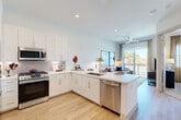 Located in Houston's desirable 77008 zip code, this well-appointed one-bedroom, one-bathroom residence offers a thoughtfully designed open-concept layout. Light wood-style flooring flows throughout, complementing the clean, contemporary aesthetic.

The kitchen is a standout feature, showcasing white shaker cabinetry, a textured tile backsplash, quartz countertops, and a full suite of stainless steel appliances including a gas range, built-in microwave, dishwasher, and refrigerator. A peninsula with bar seating provides both additional prep space and a casual dining option.

The kitchen opens seamlessly into the combined dining and living area, which is bathed in natural light from a sliding glass door leading to a private balcony. A ceiling fan enhances comfort in this airy space.

The bedroom is a tranquil retreat with natural light from multiple windows and two closets for ample storage. The bathroom features a white vanity with clean finishes and light wood flooring. A dedicated laundry area adds everyday convenience. The entrance and hallway complete the efficient, well-organized floor plan, making excellent use of every square foot in this modern Houston residence.