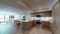 Located in the heart of Hollywood at 1825 N Las Palmas Ave, this modern single-floor residence offers a thoughtfully designed open-concept layout with clean lines and contemporary finishes throughout. Light wood-tone flooring flows seamlessly across the living, dining, and kitchen areas, creating a cohesive and welcoming ambiance.

The gourmet kitchen is a standout feature, equipped with sleek wood-grain cabinetry, a marble-style backsplash, stainless steel Bosch appliances, and a central island with a quartz countertop and undermount sink — ideal for both cooking and casual dining. Bar seating along the island connects effortlessly to the adjacent dining area, which accommodates a glass-top table and modern seating.

The living room is bright and airy, featuring recessed lighting and large sliding glass doors that open to a private outdoor space with lush palm views, filling the room with natural light and a distinctly Los Angeles atmosphere.

The bedroom is generously sized, bathed in natural light from oversized windows that frame outdoor greenery. It offers a serene retreat with clean white walls and wood-finish flooring.

The bathroom is finished with large-format dark tile flooring, a wood-framed vanity with a backlit mirror, and a glass-enclosed shower, delivering a refined, spa-like experience.