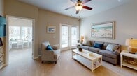 Located at 101 Grand Bahama Dr in Myrtle Beach, SC, this single-floor residence showcases a relaxed coastal aesthetic throughout. The open-concept kitchen is well-appointed with white shaker cabinetry, granite countertops, a classic subway tile backsplash, and a full suite of stainless steel appliances, including a range, microwave, and refrigerator. Light wood-style flooring anchors the kitchen and flows into an adjoining dining area, which comfortably seats four and is accented with coastal-inspired wall art. The living room is bright and welcoming, featuring plush carpet, a ceiling fan, and French doors that invite natural light and offer outdoor access. The primary bedroom provides a serene retreat with a ceiling fan, carpet flooring, and a direct en-suite bathroom featuring dark cabinetry, a white countertop vanity, and a shower-tub combination. A second bedroom accommodates twin beds, benefits from ample natural light through wide windows, and is finished with carpet and a ceiling fan. A second full bathroom mirrors the refined finishes of the primary bath. Completing the layout is a dedicated in-unit laundry room equipped with a full-size washer and dryer and wire shelving for additional storage. The overall ambiance is light, airy, and coastal throughout.
