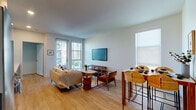 Located at 1717 N Cherokee Ave in the heart of Hollywood, Los Angeles, this single-floor residence offers a thoughtfully designed layout with modern finishes throughout. The open-concept living and dining area is bright and welcoming, featuring light hardwood flooring, clean white walls, and natural light streaming in through large windows and a glass-paned door that leads to a private balcony. The living space comfortably accommodates both a lounge area and a dining bar setup, with a wall-mounted flat-screen TV as a focal point.

The kitchen is outfitted with a streamlined galley design, combining white upper cabinetry with warm wood-toned lower cabinets and a marble-effect backsplash. Stainless steel LG appliances, including a range, microwave, and dishwasher, complement the quartz countertops, offering a functional and stylish cooking space.

The bedroom is a calm retreat with light-filled windows, a sliding closet with built-in shelving, and warm ambient lighting. The bathroom features a wood-grain vanity with a backlit mirror, white quartz countertop, and a full tub-shower combination. A dedicated in-unit laundry closet houses a stacked washer and dryer, adding everyday convenience to this well-appointed Hollywood residence.