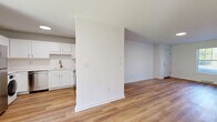 Located at 4213 Court Royale in Schenectady, NY, this single-floor, 2-bedroom, 1-bathroom home offers a clean, modern aesthetic with thoughtful updates throughout. Light wood-look flooring runs seamlessly across all living areas, complementing the crisp white walls and trim that give the space a bright, airy feel.

The combined kitchen and living area serves as the heart of the home. The kitchen is well-appointed with white shaker-style cabinetry, light countertops, gold-toned hardware, and a full suite of stainless steel appliances including a refrigerator, dishwasher, and range. An in-unit washer is also conveniently integrated into the kitchen space.

The living area flows naturally from the kitchen and features a front-facing window fitted with blinds, allowing for natural light while maintaining privacy. Both bedrooms are comfortably sized, with the primary bedroom offering generous square footage, white walls, and windows that look out to greenery. The second bedroom also benefits from natural light through a window with outdoor views.

The bathroom is finished with white tile flooring, a white vanity with gold fixtures, a rounded mirror with a modern light bar, and a full tub-shower combination. The home is set on a landscaped lot with mature trees and green lawn visible from the exterior.