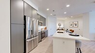 Located at 620 W Colfax Ave in Denver, Colorado, this well-appointed 2-bedroom, 2-bathroom residence offers a thoughtfully designed single-floor layout with modern finishes throughout. Light wood-tone flooring flows seamlessly across the open-concept living, dining, and kitchen areas, creating a cohesive and airy atmosphere. The contemporary kitchen is a standout feature, equipped with stainless steel appliances including a French door refrigerator, built-in microwave, and range, all complemented by sleek gray flat-front cabinetry that extends to the ceiling for ample storage. A large white waterfall-edge island provides generous counter space and bar seating for three, making it ideal for both meal prep and casual dining. The open living room receives natural light through large windows and connects directly to the dining area, reinforcing the spacious feel. Both bedrooms are comfortably scaled, with the primary bedroom featuring access to a private balcony and generous closet space. The secondary bedroom is equally bright and well-proportioned. The two bathrooms are finished with clean white tile, floating gray vanities with white countertops, and a tub-shower combination. Additional conveniences include a pantry, four closets, and a hallway connecting the private spaces. The overall aesthetic is clean, modern, and move-in ready.