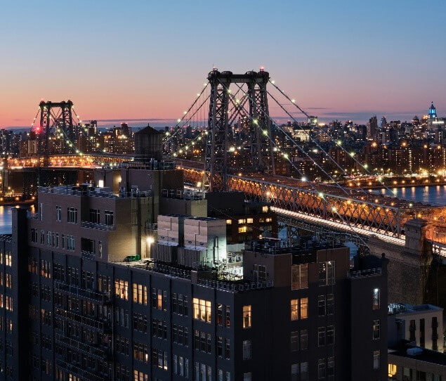 A stunning view of the Williamsburg Bridge, illuminated by the Manhattan skyline