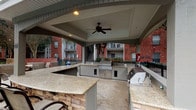 This residential community offers a thoughtfully designed set of shared amenities and service areas that cater to everyday convenience and outdoor leisure. The mail center is a standout functional space, featuring walls lined with rows of individual mailboxes and secure parcel lockers finished in a neutral gray tone. Light wood-look flooring and recessed lighting lend the room a clean, modern aesthetic, while a central white countertop island provides a convenient surface for sorting correspondence. The well-lit, single-floor layout ensures easy accessibility for all residents.

Adjacent to the building, the outdoor amenity area is equally impressive. A generously sized swimming pool with vibrant turquoise water is bordered by a classic brick-trimmed pool deck, furnished with lounge chairs ideal for relaxing. Mature trees and lush greenery provide a natural backdrop, enhancing the sense of privacy and tranquility.

A covered outdoor kitchen and entertainment pavilion completes the amenity offering. Equipped with stainless steel grills, stone-accented countertops with granite surfaces, and ceiling fans overhead, this space is designed for comfortable outdoor gatherings in any season. Together, these amenities reflect a community built with both practicality and quality of life in mind.