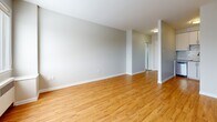 Located at 1379 Princess St in Kingston, Ontario, this one-bedroom, one-bathroom unit offers a clean, functional layout designed to maximize its compact footprint. The living room is a bright, open space highlighted by a large window that frames outdoor views of surrounding trees, allowing natural light to pour across warm hardwood-style flooring that extends throughout the main living areas. A radiator heating unit beneath the window ensures year-round comfort. The neutral grey-toned walls and white trim create a crisp, understated palette throughout. The bedroom is a well-proportioned private retreat, also featuring a window with natural light, a radiator, and hardwood-style flooring, offering a calm and comfortable atmosphere. Three closets provide generous storage across the unit. The kitchen is a dedicated, enclosed space with its own fixtures, offering efficient functionality. The bathroom is outfitted with a full soaker tub and shower combo with white tile surround, a vanity with storage, and distinctive earthy stone-patterned tile flooring that adds a warm contrast to the otherwise neutral interior. The overall layout flows logically from the entry through the living areas to the bedroom and bathroom, making practical use of every square foot.