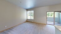 Located in Edgewood, Washington, this one-bedroom, one-bathroom residence offers a well-designed single-floor layout that makes efficient use of its compact footprint. The open-concept living area is bright and welcoming, featuring soft carpet flooring, neutral tones, and a large window that draws in natural light and frames views of the surrounding greenery. A sliding door provides access to an outdoor area, further enhancing the sense of openness.

The kitchen is a standout feature, equipped with rich dark wood cabinetry extending to the upper walls, a suite of black appliances including a refrigerator, range, and built-in microwave, and crisp white countertops. A peninsula with a built-in sink adds both prep space and a natural divider between the kitchen and living areas. Track lighting overhead provides focused illumination throughout.

The bedroom is a comfortable retreat with plush carpeting, a large closet with sliding doors, a window with outdoor views, and a baseboard heater. An adjacent door leads to a dedicated laundry area, adding everyday convenience. The bathroom features warm wood-toned cabinetry, a white vanity countertop with an integrated sink, a large mirror, and a tub/shower combination, all set on easy-to-maintain hardwood-style flooring. The overall aesthetic is clean, modern, and functional.