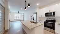 Located at 2789 Satellite Blvd in Duluth, GA, this well-appointed 1-bedroom, 1-bathroom unit offers a thoughtfully designed single-level layout with modern finishes throughout. The open-concept kitchen and living area serves as the heart of the home, anchored by a large central island with granite countertops and a matte black pull-down faucet, illuminated by stylish industrial pendant lighting. The kitchen is equipped with a full suite of stainless steel appliances — including a refrigerator with ice maker, electric range, over-the-range microwave, and dishwasher — all complemented by crisp white shaker cabinetry with black hardware and light wood-tone flooring. The living area is bright and airy, benefiting from natural light streaming through large windows with blinds and featuring a ceiling fan overhead. The bedroom is carpeted for comfort, includes a ceiling fan, a walk-in closet, and a window with outdoor views. The bathroom is clean and modern, with granite countertops, white shaker cabinetry, matte black fixtures, and a full tub-shower combination with tiled surround and light wood-tone flooring. This unit combines functional design with contemporary aesthetics for comfortable everyday living.