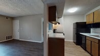 This single-floor unit is located at 7901 South Yale Avenue in Tulsa, Oklahoma, offering a practical and well-organized layout throughout. The kitchen is equipped with dark wood cabinetry, a light-toned countertop, a built-in range with overhead ventilation, a black refrigerator, and a dishwasher. Wood-look vinyl flooring runs through the kitchen and connects seamlessly to the adjacent living area. The living space is generously sized, featuring the same wood-look flooring, neutral taupe walls, and a large sliding glass door fitted with vertical blinds that allows an abundance of natural light to fill the room. The bedrooms are carpeted and offer comfortable dimensions, each with windows that bring in additional natural light. Two full bathrooms serve the unit, both featuring white tile tub-shower combinations, wood-look flooring, and clean, functional fixtures. One bathroom includes a double-sink vanity with dark wood cabinetry and a granite-style countertop, while the other conveniently houses a stacked washer and dryer unit. Throughout the space, a textured ceiling adds consistent character, and neutral tones create a cohesive, move-in-ready atmosphere.