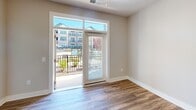 Located in Charlotte, NC, this well-appointed one-bedroom, one-bathroom residence offers a thoughtfully designed single-floor layout with modern finishes throughout. The open-concept kitchen and dining area serves as the heart of the home, showcasing crisp white shaker cabinetry, granite countertops, a classic subway tile backsplash, stainless steel appliances including a dishwasher and refrigerator, and a central island with pendant lighting — ideal for both meal prep and casual dining. Wood-look flooring runs through the main living areas, adding warmth and continuity to the space. A sliding glass door opens to a private balcony overlooking a resort-style pool and courtyard, flooding the living area with natural light and scenic views. The bedroom features plush carpeting, a ceiling fan, and windows that frame views of the surrounding community. A spacious walk-in closet with wire shelving provides generous storage. The bathroom is equipped with an accessible tub and shower combination, complete with grab bars and a bench seat, reflecting thoughtful, inclusive design. Neutral tones and clean lines throughout create a bright, inviting ambiance suitable for comfortable everyday living.