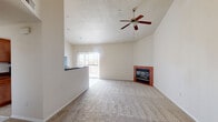 This single-floor residence offers a thoughtfully designed layout that balances open living spaces with practical amenities. The expansive living room immediately draws attention with its soaring vaulted ceilings, a textured ceiling finish, and a ceiling fan that enhances air circulation throughout. A brick-surround corner fireplace serves as a warm focal point, while a sliding glass door floods the space with natural light and provides access to a private balcony. Neutral-toned carpet extends throughout the living area and bedrooms, contributing to a clean and cohesive aesthetic. The kitchen is well-appointed with warm wood cabinetry, dark countertops, tile flooring, and a full suite of black appliances including a gas range, microwave, and refrigerator. A breakfast bar connects the kitchen to the living area, creating a natural flow ideal for entertaining. The bedroom features plush carpeting and a mirrored sliding-door closet that adds depth to the room. The primary bathroom is equipped with wood-toned cabinetry, a single vanity with ample counter space, wood-look flooring, and a glass-enclosed walk-in shower. A secondary bathroom offers a full tub-shower combination with classic white tile surround. Completing the space is a dedicated in-unit laundry area with side-by-side washer and dryer hookups.