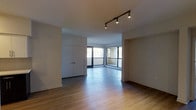 This single-floor space offers a clean, modern interior highlighted by warm hardwood flooring that runs throughout the main living area. A standout feature is the corner arrangement of floor-to-ceiling windows, which floods the space with abundant natural light and provides open views of the surrounding exterior. The windows create an airy, expansive feel, making the space feel larger than its footprint suggests.

Track lighting mounted on the ceiling provides adjustable, directed illumination, complementing the natural light and adding a contemporary design touch. The neutral white walls and smooth ceilings contribute to a bright, minimalist aesthetic throughout.

A set of built-in closet doors with a clean, flush design is integrated along one wall, offering practical storage while maintaining the uncluttered look of the space. The open layout allows for flexible furniture arrangements, making it well-suited for a variety of uses.

Overall, the space presents a modern, light-filled environment with functional design elements, durable flooring, and a seamless connection to the outdoors through its generous glazing.