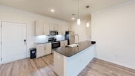 Located at 910 Ardmore Alcoa Way in Louisville, Tennessee, this well-appointed single-story residence offers three bedrooms and three full bathrooms across a thoughtfully designed floor plan. The open-concept kitchen and living area serves as the heart of the home, showcasing white shaker cabinetry, dark granite countertops, a subway tile backsplash, a farmhouse sink, and stainless steel appliances including a dishwasher and refrigerator. Elegant pendant lighting and crown molding add refined touches, while durable wood-look luxury vinyl plank flooring extends throughout the main living spaces. The living area is bright and airy, with natural light streaming in through multiple windows offering views of the surrounding neighborhood. The generously sized primary bedroom features plush carpet, multiple windows, and connects to a private bathroom with a tub-shower combination and a spacious walk-in closet with built-in shelving. Additional bedrooms are carpeted and well-proportioned, each with ample closet space. The bathrooms are finished with matching dark granite vanity tops and light wood-look flooring. A dedicated laundry room and an impressive seven closets throughout the home provide exceptional storage. The clean, neutral color palette and modern finishes create a cohesive and move-in-ready atmosphere throughout.