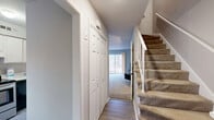 This 830 square foot townhouse in Charlotte, NC, offers a blend of urban convenience and natural surroundings. The two-story layout comprises 2 bedrooms and 1 bathroom, efficiently utilizing space across its 430 sq ft ground floor and 400 sq ft upper level.

The open-plan living area features a modern aesthetic with neutral tones and carpeted floors. The living room is furnished with a sleek entertainment center and comfortable seating, adorned with contemporary artwork. Large windows provide ample natural light and views of the surrounding wooded area.

The kitchen boasts updated appliances, including a stainless steel refrigerator and oven, complemented by white cabinetry and light-colored flooring. A sliding glass door in the living area leads to an outdoor space, seamlessly connecting indoor and outdoor living.

Bedrooms are well-proportioned, with the primary bedroom measuring 160 sq ft. They feature carpeted floors, large windows, and space for entertainment systems. The bathroom, though not extensively detailed, likely includes standard fixtures.

The property's exterior showcases horizontal siding and is nestled among trees, offering a serene backdrop. This townhouse presents an ideal option for those seeking a compact, modern living space with easy access to nature in Charlotte's urban setting.