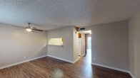 Located at 5757 Wooldridge Rd in Corpus Christi, Texas, this single-story residence offers a functional and comfortable layout with consistent design details throughout. The main living area is open and well-proportioned, showcasing durable wood-look flooring, neutral-toned walls, and a textured ceiling. A ceiling fan provides year-round comfort, while natural light filters in through windows fitted with blinds. A pass-through opening connects the living space directly to the kitchen, enhancing the sense of openness and flow between the two areas. The kitchen is well-appointed with rich, warm-toned cabinetry, granite-style countertops, a tile backsplash, and white appliances including a refrigerator and range. Light tile flooring lines the kitchen, complementing the wood-look flooring found throughout the rest of the home. The bedroom is generously sized with its own ceiling fan, wood-look flooring, and a sliding glass door that opens to an outdoor space, allowing for natural light and fresh air. A rich red-toned interior door adds a warm accent. The bathroom includes a full-size soaking tub and shower combination with clean, white surrounds and chrome fixtures. A dedicated entry area with a six-panel door provides a clear transition into the home.