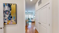 This thoughtfully designed single-floor residence offers two bedrooms and three bathrooms within a well-organized open-concept floor plan. A welcoming entryway with hardwood flooring leads into the combined kitchen and living area, where soaring ceilings and large sliding glass doors with transom windows above flood the space with natural light and provide direct access to a private balcony.

The kitchen is a standout feature, showcasing rich dark wood cabinetry reaching to the ceiling, stainless steel appliances, a tile backsplash, and a generous white quartz island with seating — ideal for casual dining. The living area is spacious and bright, enhanced by a ceiling fan and seamless balcony access.

Both bedrooms are well-proportioned, each featuring carpeted floors, ceiling fans, and roller-shaded windows. The primary bedroom includes its own en-suite bathroom, which is finished with marble-style tile flooring, a dual-sink vanity with granite countertops, gray cabinetry, and a glass-enclosed walk-in shower. The additional bathrooms maintain the same refined aesthetic with consistent marble-style tile and quality fixtures throughout, contributing to a cohesive and polished overall ambiance.