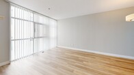 Located at 33 S 3rd St in the heart of downtown San Jose, CA, this one-bedroom, one-bathroom unit offers a well-designed layout across a single floor. Light hardwood flooring flows throughout the main living areas, complementing a neutral color palette that gives the space a clean, contemporary feel.

The open living area is bathed in natural light thanks to floor-to-ceiling windows fitted with vertical blinds, offering views of the surrounding urban landscape. A pendant light fixture adds a warm focal point to the room. The kitchen is efficiently designed in a U-shape configuration, featuring white cabinetry with dark countertops, stainless steel appliances — including a refrigerator, microwave, and electric range — and recessed ceiling lighting.

The bedroom is carpeted for comfort and includes a dedicated walk-in closet with built-in shelving, providing ample storage. A small window allows for natural light. The unit also features two additional closets for further storage convenience.

The full bathroom is finished with light wood-look flooring, white cabinetry, a dual-mirror vanity with a white countertop, and a soaking tub. A utility room and an entrance area round out the thoughtfully organized floor plan, making this unit both functional and stylish for urban living.