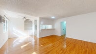 Located at 10535 Lindley Ave in the Porter Ranch neighborhood of Los Angeles, this 2-bedroom, 2-bathroom home offers a practical and comfortable single-floor layout. Warm-toned hardwood flooring flows throughout the main living areas and bedrooms, providing a bright, cohesive look complemented by white walls and textured ceilings.

The open-concept living and kitchen area serves as the heart of the home. The living room features a ceiling fan, built-in shelving, and generous natural light. The kitchen is laid out in a galley style, equipped with white cabinetry, ample counter space, a stainless steel sink with a modern black faucet, and white appliances including a range and refrigerator. Tile flooring anchors the kitchen zone, and a breakfast bar connects it seamlessly to the living area.

The spacious primary bedroom offers room-darkening potential with sliding windows, a wall-mounted A/C unit, and access to a well-sized walk-in closet. The second bedroom is bright and comfortable, with a window framing views of surrounding greenery. Three closets total are distributed throughout the home for generous storage.

The two bathrooms are cleanly appointed — one features a glass-enclosed tile shower, while the other includes a full soaking tub. A connecting hallway ties all rooms together efficiently, completing this well-organized home.