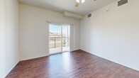 This single-floor residence in the Gateway area of Rapid City, South Dakota, offers a well-organized layout with a clear separation between living and sleeping areas. The living room serves as the central gathering space, finished with rich, dark hardwood-style flooring and a ceiling fan overhead. Sliding glass doors open directly onto a private balcony with a metal railing, providing open views of the surrounding neighborhood and rolling landscape beyond.

The kitchen is positioned adjacent to the living area and features dark espresso cabinetry, light granite-style countertops, and a full suite of black appliances, including a refrigerator and dishwasher. Wood-look flooring continues through this space, and a dedicated closet nearby houses in-unit laundry appliances.

The bedrooms are carpeted in neutral tones and receive natural light through sliding and standard windows, several of which frame views of the neighborhood. One bedroom includes a reach-in closet and direct access to a full bathroom. The bathroom is finished with tile flooring, a dark vanity with a granite-style countertop, and a tub-shower combination. Throughout the unit, crisp white walls and clean lines create a bright, functional living environment.