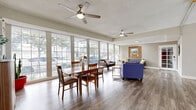 Located on Magnolia Boulevard in Los Angeles, this single-floor space offers a thoughtfully arranged layout that combines a living room, dining area, and kitchen into a cohesive and functional environment. Throughout the space, light-toned wood-style flooring provides a clean, contemporary foundation that ties each area together seamlessly.

The living room is a standout feature, anchored by floor-to-ceiling grid-pane windows that span an entire wall, inviting abundant natural light and offering open views of the surrounding streetscape and greenery. The bright, airy atmosphere is further enhanced by neutral gray walls and a textured ceiling. French-style interior doors with glass panes contribute an elegant architectural detail while maintaining visual connectivity between rooms.

The combined dining area is generously proportioned, accommodating a full dining table beneath a ceiling fan that promotes comfortable airflow. Large windows continue the theme of natural illumination, making the space feel open and welcoming.

The kitchen is well-appointed with white cabinetry featuring gold hardware, granite-style countertops, a gas range, and a full-size stainless steel refrigerator. A built-in dining nook with a wood counter and seating provides a casual dining option alongside the dedicated dining room. A window above the nook brings in additional natural light. The overall ambiance of the space is bright, clean, and inviting.