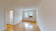 Located at 900 W Montgomery Ave in Bryn Mawr, PA, this single-floor unit offers a clean, well-maintained layout designed for comfortable everyday living. Throughout the main living areas, gleaming hardwood floors in a warm honey tone reflect natural light streaming in through multiple windows fitted with blinds, creating a bright and inviting atmosphere. The living space is open and airy, with crisp white walls, classic baseboards, and a neutral palette that provides a versatile backdrop for any décor style. An elegant arched doorway connects the living area to additional spaces, adding a touch of architectural character. The galley-style kitchen is efficiently organized, featuring white cabinetry with wood-trimmed accents, white appliances including a range and refrigerator, ample counter space, a stainless steel sink, and light tile flooring — providing all the essentials in a practical layout. The bedroom is generously proportioned, offering two closets for ample storage and windows that bring in natural light. The bathroom is finished with classic mosaic tile flooring, a white vanity, a tub-shower combination with white tile surround, and a window for natural ventilation, maintaining a clean and timeless aesthetic throughout.