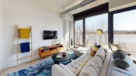 Located at 1900 Half St SW in Washington, DC's vibrant Southwest Waterfront neighborhood, this modern single-floor residence offers a thoughtfully designed layout with contemporary finishes throughout. The open-concept living area is anchored by expansive floor-to-ceiling windows that frame sweeping views of the Anacostia River, flooding the space with natural light and creating a seamless connection to the waterfront outside. Exposed industrial ductwork adds an urban loft character to the bright, white-walled interior. The kitchen is outfitted with crisp white shaker cabinetry, dark stone countertops, a marble-style backsplash, and a full suite of stainless steel appliances, combining style with functionality. A dedicated sitting nook alongside the large corner windows provides an ideal vantage point to take in the river scenery. The bedroom offers a calm, neutral retreat with clean white walls, natural light from a tall window, and tasteful décor. The bathroom features dark subway tile in the walk-in glass-enclosed shower, complemented by neutral floor tile, a white vanity with dark countertop, and recessed lighting, delivering a polished, spa-like finish. This residence blends industrial-modern design with an enviable waterfront setting.
