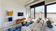 Located at 1900 Half St SW in Washington, DC's vibrant Southwest Waterfront neighborhood, this modern single-floor residence offers a thoughtfully designed layout with contemporary finishes throughout. The open-concept living area is anchored by expansive floor-to-ceiling windows that frame sweeping views of the Anacostia River, flooding the space with natural light and creating a seamless connection to the waterfront outside. Exposed industrial ductwork adds an urban loft character to the bright, white-walled interior. The kitchen is outfitted with crisp white shaker cabinetry, dark stone countertops, a marble-style backsplash, and a full suite of stainless steel appliances, combining style with functionality. A dedicated sitting nook alongside the large corner windows provides an ideal vantage point to take in the river scenery. The bedroom offers a calm, neutral retreat with clean white walls, natural light from a tall window, and tasteful décor. The bathroom features dark subway tile in the walk-in glass-enclosed shower, complemented by neutral floor tile, a white vanity with dark countertop, and recessed lighting, delivering a polished, spa-like finish. This residence blends industrial-modern design with an enviable waterfront setting.