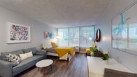 Located at 3125 Sinton Rd in Colorado Springs, Colorado, this single-floor studio unit offers a thoughtfully designed open-concept layout that seamlessly combines living, sleeping, and dining areas. The main living space is a standout, featuring a full-width sliding glass door flanked by vertical blinds that flood the room with abundant natural light and provide direct access to the outdoors. Rich wood-look plank flooring runs throughout, adding warmth and visual continuity across the entire unit.

The sleeping and living area is generously proportioned, accommodating both a full-sized bed and a seating area with ease. Soft gray walls serve as a neutral backdrop, complemented by vibrant accent artwork that adds a pop of color to the space. A compact kitchenette is efficiently designed with white shaker-style cabinetry, granite-look countertops, a stainless steel refrigerator, microwave, and a single-basin sink — providing all essential cooking amenities in a streamlined footprint.

The bathroom is neatly appointed with wood-toned cabinetry, an oval overhead light fixture, a framed mirror, and coordinating wood-look flooring. A short entry corridor with a paneled white door leads into the main living area, providing a clear sense of transition within the unit. The textured ceiling is consistent throughout, adding a classic finishing detail to this well-appointed Colorado Springs studio.