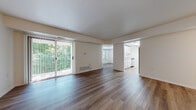 Located at 2320 Timberbrook Dr SE in Grand Rapids, Michigan, this single-floor residence offers a clean, functional layout with a bright and open feel throughout. The expansive living area is finished with rich hardwood-style flooring and features a large sliding glass door that floods the space with natural light and provides views of the surrounding mature trees and greenery, creating a serene connection to the outdoors. The open floor plan flows naturally into a secondary living or dining area, maintaining a sense of spaciousness across the main living spaces. The kitchen is efficiently designed in a galley style, outfitted with white cabinetry, light countertops, and stainless steel appliances including a dishwasher, offering a practical and tidy workspace. The bedroom is generously sized, featuring a large window with leafy outdoor views, a double-door closet, and the same warm hardwood-style flooring found throughout the home. The bathroom is clean and well-appointed, featuring a full tub-shower combination, a white vanity, and matching light wood flooring that ties the space together. Neutral wall tones and consistent flooring throughout create a cohesive and move-in-ready atmosphere ideal for comfortable everyday living.