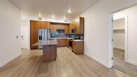 Located at 1400 E 1800 S in Clearfield, Utah, this well-appointed 2-bedroom, 2-bathroom residence offers a thoughtfully designed single-level layout. The open-concept kitchen and living area serves as the heart of the home, showcasing warm wood cabinetry, a slate-toned tile backsplash, stainless steel appliances including a refrigerator, range, microwave, and dishwasher, white quartz-style countertops, and a central island with additional seating space. Light wood-style flooring runs throughout the main living areas, lending a clean, contemporary feel. The living room receives natural light through large windows and features a ceiling fan and direct access to a private balcony. Both bedrooms are carpeted for comfort, each equipped with ceiling fans, generous windows with blinds, and ample closet space — four closets are distributed throughout the unit. The spacious primary bedroom includes a walk-in closet with built-in shelving and hanging rods. The bathrooms are finished with wood-toned vanities, white countertops, large mirrors, and wood-look tile flooring. A hallway connects the living areas to the bedrooms, maintaining a functional and organized flow throughout this modern Clearfield residence.