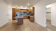 Located at 1400 E 1800 S in Clearfield, Utah, this well-appointed 2-bedroom, 2-bathroom residence offers a thoughtfully designed single-level layout. The open-concept kitchen and living area serves as the heart of the home, showcasing warm wood cabinetry, a slate-toned tile backsplash, stainless steel appliances including a refrigerator, range, microwave, and dishwasher, white quartz-style countertops, and a central island with additional seating space. Light wood-style flooring runs throughout the main living areas, lending a clean, contemporary feel. The living room receives natural light through large windows and features a ceiling fan and direct access to a private balcony. Both bedrooms are carpeted for comfort, each equipped with ceiling fans, generous windows with blinds, and ample closet space — four closets are distributed throughout the unit. The spacious primary bedroom includes a walk-in closet with built-in shelving and hanging rods. The bathrooms are finished with wood-toned vanities, white countertops, large mirrors, and wood-look tile flooring. A hallway connects the living areas to the bedrooms, maintaining a functional and organized flow throughout this modern Clearfield residence.