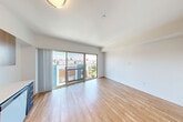 Located at 8022 15th Ave NW in Seattle's Crown Hill neighborhood, this one-bedroom, one-bathroom unit offers a thoughtfully designed open-concept layout spread across a single floor. Warm hardwood flooring flows consistently throughout the living areas and bedroom, creating a cohesive and inviting atmosphere.

The combined kitchen and living area serves as the heart of the unit. The kitchen features sleek navy-blue lower cabinetry paired with warm wood-toned upper cabinets, stainless steel appliances including a dishwasher, microwave, and range, and a light countertop with an integrated sink. Floor-to-ceiling sliding glass doors in the living area flood the space with natural light and open to a private balcony overlooking the surrounding Seattle neighborhood, providing pleasant outdoor views and ventilation.

The bedroom is a quiet, well-proportioned retreat finished with the same hardwood flooring and crisp white walls. Frosted glass sliding doors add a modern touch while offering flexible access. A dedicated closet provides practical storage solutions.

The bathroom is clean and functional, featuring a full soaking tub and shower combination, a wood-toned vanity with a light stone countertop, an undermount sink, and a large mirror. In-unit laundry further enhances everyday convenience. The overall design is modern and minimal, making this a well-equipped urban residence.