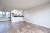 Located at 1825 Poggi St in Alameda, California, this one-bedroom, one-bathroom residence offers a thoughtfully designed single-floor layout. The open-concept kitchen and living area serves as the heart of the home, featuring wood-look flooring, a textured ceiling, and a ceiling fan that enhances airflow throughout. The kitchen is equipped with crisp white shaker cabinetry, gray quartz-style countertops, stainless steel appliances including a gas range and refrigerator, and a peninsula that provides additional prep and seating space. The living area is bright and airy, benefiting from a sliding glass door that opens to a private balcony with a wood-panel privacy screen, allowing natural light to pour in. A wall-mounted heater unit provides efficient climate control in the living space. The bedroom is carpeted for comfort, offering a sliding-door closet with built-in shelving and a window framing an outdoor view. The full bathroom is clean and functional, featuring a full-size soaking tub with shower, wood-look tile flooring, and neutral toned walls. This residence combines practical design with modern finishes in a convenient Alameda location.