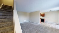 Located at 1112 Ashberry Village Dr in Columbus, Ohio, this two-story home offers a functional and practical layout spread across two floors. The main level houses the combined kitchen and living area, while the upper floor accommodates the bedrooms and bathroom.

The galley-style kitchen is a standout feature, outfitted with rich dark wood cabinetry, granite-style countertops, a double sink, black appliances including a range and refrigerator, and wood-look flooring. In-unit laundry hookups are also present. The adjacent living room provides a comfortable gathering space with a mix of carpeting and hard-surface flooring, a baseboard heater, and a wall-mounted air conditioning unit, with natural light streaming in through a window fitted with blinds.

Both bedrooms are carpeted and finished in neutral tones, each equipped with ceiling fans and windows that bring in natural light. The primary bedroom includes a wall-mounted air conditioning unit and closet access. The full bathroom features wood-look flooring, a vanity with granite-style countertops and dark wood cabinetry, a toilet, and a tub-shower combination. Throughout the home, textured ceilings, neutral wall colors, and clean white trim create a consistent, understated aesthetic.
