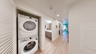 Located in Seattle's vibrant Capitol Hill neighborhood, this well-appointed one-bedroom, one-bathroom residence at 1100 Boylston Ave offers a smartly efficient layout with contemporary finishes throughout. Light hardwood flooring flows seamlessly across every room, creating a warm, cohesive aesthetic.

The living room serves as the heart of the unit, featuring expansive floor-to-ceiling windows that invite abundant natural light and offer views of the surrounding cityscape. A wall-mounted mini-split system provides climate control, while a textured concrete-style accent panel adds an artistic, modern touch.

The galley-style kitchen is outfitted with white subway tile backsplash, crisp white cabinetry, stainless steel appliances, and a sleek undermount sink — maximizing both function and style in a compact footprint.

The bedroom is a calm retreat, offering a built-in closet and a narrow clerestory window that allows soft natural light while maintaining privacy.

The bathroom features a wide vanity with gray cabinetry, white quartz countertops, and a large wall mirror with bright overhead lighting. A hallway niche houses a full-size stacked washer and dryer, adding exceptional convenience. Recessed lighting throughout completes the clean, modern ambiance of this thoughtfully designed Seattle residence.