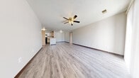 This single-floor home offers five bedrooms and three bathrooms within a thoughtfully arranged floor plan. The open-concept living room and kitchen form the heart of the home, featuring light gray luxury vinyl plank flooring, neutral walls, and a ceiling fan with built-in lighting. The kitchen is equipped with black appliances, including a refrigerator and electric range, complemented by light wood cabinetry and laminate countertops. A kitchen island provides additional workspace and separation from the living area.

A sliding glass door in the living space allows natural light to pour in and provides outdoor access. The bedrooms are carpeted and connected via a central hallway, with the primary bedroom offering a comfortable footprint and natural light from a window. The bathrooms feature clean white finishes, including a tub-shower combination and a single vanity with a mirror. Additional conveniences include a dedicated laundry room, a hallway closet for storage, and a textured ceiling throughout. The overall aesthetic is clean, neutral, and move-in ready.