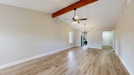Located at 5050 Woodland Park Dr in Beaumont, TX, this single-story, 2-bedroom, 4-bathroom home offers a well-designed layout across a comfortable and functional floor plan. The main living area is an immediate standout, featuring soaring vaulted ceilings accented by a rich exposed wood beam, a ceiling fan, and an elegant chandelier. A gray brick fireplace with a wood mantel serves as a focal point, complemented by light wood-look flooring and neutral-toned walls that create a bright, welcoming ambiance throughout. Natural light flows in through multiple windows fitted with blinds. The galley-style kitchen is efficiently designed with gray shaker cabinets, white quartz countertops, black hardware accents, stainless steel appliances including a refrigerator, range, and dishwasher, and an in-unit washer and dryer. Both bedrooms are well-proportioned, featuring the same light wood flooring, ceiling fans, and ample natural light. The primary bedroom includes a generous closet. The four bathrooms are finished with white shaker vanities, quartz countertops, matte black fixtures, and full tub-shower combinations. Two dedicated closets provide additional storage throughout the home.