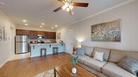 Located at 259 S Maestri Rd in Tontitown, Arkansas, this well-appointed single-story home offers a thoughtfully designed open-concept layout that seamlessly connects the living, dining, and kitchen areas. The living room is bright and welcoming, featuring warm hardwood flooring, crown molding, a ceiling fan with light fixture, and large windows dressed with grommet curtains that invite generous natural light. A glass door leads to an outdoor area, enhancing the sense of openness.

The kitchen is a standout feature, showcasing rich dark wood cabinetry that reaches the ceiling, stainless steel appliances including a refrigerator, microwave, and range, and a granite-topped peninsula with bar seating for two — ideal for casual dining or entertaining. Recessed lighting illuminates the space efficiently.

The bedrooms are comfortably sized, each featuring ceiling fans, plush carpeting, and windows with blinds and curtain panels that allow for natural light and privacy. The neutral color palette throughout creates a calm, cohesive atmosphere.

The bathroom is clean and functional, finished with light tile flooring and a full tub-shower combination. Hallway access provides convenient separation between living and sleeping areas, contributing to a practical and comfortable single-floor floor plan.