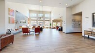 Located at 800 Reliant Way in American Canyon, California, this expansive single-story community clubhouse offers a generously proportioned and thoughtfully designed gathering space. The interior is anchored by a dramatic double-height great room flooded with natural light through floor-to-ceiling windows and clerestory windows above, providing sweeping views of the outdoor pool area and surrounding landscaping. A sleek, tile-surround linear fireplace serves as a striking focal point, complemented by warm wood-look tile flooring that flows throughout the space.

The living and dining areas are open and airy, furnished with leather seating, reclaimed wood coffee tables, and tasteful wall art, creating a welcoming and social atmosphere. A dedicated lounge nook with large windows offers a quieter retreat for smaller gatherings. The reception entry features soaring ceilings, an elegant chandelier, and grand double doors that set a refined tone upon arrival.

A corridor with large interior windows leads to a well-equipped fitness center, visible from the hallway. Additional seating areas with natural light and outdoor views provide versatile spaces for relaxation or informal meetings. Throughout, the design balances modern architectural details with warm, earthy furnishings to create an inviting and functional community environment.