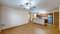 This 1,060-square-foot, single-floor unit at 305 S Fifth St in Ames, Iowa offers three bedrooms, two bathrooms, and a practical, well-organized layout. The open-concept kitchen and living area serves as the heart of the home, featuring warm medium-toned wood cabinetry, granite-look countertops, stainless steel appliances including a refrigerator, electric range, and microwave, and a peninsula breakfast bar with pendant lighting overhead. Wood-look plank flooring runs throughout the main living areas, adding warmth and continuity. The primary bedroom measures 170 square feet and includes a spacious walk-in closet outfitted with wire shelving for ample storage. The two additional bedrooms are carpeted, each featuring a ceiling fan and natural light from windows with views of surrounding greenery. One bedroom features its own closet with built-in rod and shelving. The primary bathroom includes warm wood cabinetry, a wide vanity with generous counter space, tile flooring, and a bathtub. A dedicated laundry room houses a full-size washer and dryer set on tile flooring with overhead wire shelving. Two closets provide additional storage throughout the unit, completing this functional and comfortable home.