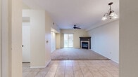 This well-designed two-bedroom, two-bathroom residence at 411 King St in La Crosse, WI offers a comfortable and functional single-floor layout. The open living room serves as the heart of the home, featuring a tiled fireplace with a dark mantle, a ceiling fan, and plush carpeting that transitions to tile flooring in the entry areas. A sliding glass door floods the space with natural light and opens directly onto a private patio with urban views. The adjacent dining area is accented by a hanging chandelier, creating a warm atmosphere for entertaining. The kitchen is outfitted with white cabinetry, white appliances, a U-shaped counter layout, and a peninsula that provides additional prep space, all topped with tile flooring and a skylight-style overhead fixture. Both bedrooms feature soft carpet, natural light from windows, and generous closet space — the primary bedroom includes mirrored sliding closet doors that enhance the sense of space. The bathrooms are finished with tile flooring and clean, functional fixtures. A dedicated in-unit laundry room accommodates full-sized washer and dryer units. Three closets, a pantry, and two hallways round out the thoughtfully organized floor plan.