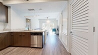 Located at 2580 Bancroft Way in Berkeley, CA, this thoughtfully designed single-floor unit offers a clean, modern aesthetic throughout. The open-concept kitchen and living area serves as the heart of the space, featuring warm wood-tone cabinetry, granite countertops, and a peninsula with bar seating — ideal for casual dining or socializing. Stainless steel appliances, including a refrigerator, microwave, and dishwasher, provide functional convenience. Pendant lighting and recessed fixtures illuminate the kitchen, while a ceiling fan enhances the comfortable living area beyond. Large windows flood the living room with abundant natural light and offer pleasant views of surrounding greenery, creating a bright and welcoming atmosphere. Wood-look vinyl flooring runs throughout the main living areas, adding warmth and easy maintenance. The bedrooms are carpeted for comfort, each equipped with built-in storage beds featuring drawers, a dedicated desk area, shelving, and a ceiling fan — thoughtfully outfitted for productive living. The bathroom is finished with clean white subway tile in the tub-shower surround, a granite-top vanity, and coordinating wood-tone cabinetry, maintaining the unit's consistent modern style. The overall ambiance is light, airy, and functional.