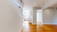 Located at 17 Forest St in Cambridge, MA, this one-bedroom, one-bathroom unit offers a thoughtfully designed layout with a clean, minimalist aesthetic. Warm hardwood floors run throughout the space, complementing the bright white walls and recessed lighting that create an open, airy feel.

The living area flows seamlessly toward the kitchen, which is outfitted with modern white cabinetry, light quartz countertops, stainless steel appliances including a gas range, oven, and microwave, and a window that draws in natural light. A wall-mounted mini-split system provides efficient climate control in the main living space.

The bedroom is a well-proportioned, tranquil retreat featuring large windows that offer neighborhood views and fill the room with abundant natural light. The hardwood floors continue here, maintaining a consistent, cohesive look.

The bathroom is finished with neutral large-format tile, a sleek white vanity, and a glass-enclosed walk-in shower equipped with chrome fixtures and a frosted privacy window, lending the space a clean, spa-like quality.

Two hallways connect the rooms efficiently, and the overall layout makes practical use of the available square footage. The unit's neutral palette, modern finishes, and natural light create a comfortable and functional living environment in a sought-after Cambridge location.