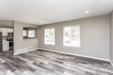 This two-floor home presents a clean, modern aesthetic with thoughtfully updated finishes throughout. The main living area is open and inviting, featuring light-toned luxury vinyl plank flooring, neutral taupe walls, and a textured ceiling with recessed lighting. Large windows fitted with horizontal blinds allow generous natural light to fill the space while offering views of the surrounding neighborhood.

The kitchen connects seamlessly to the living area via a pass-through counter, and is outfitted with crisp white cabinetry, sleek bar-pull hardware, and striking marble-veined quartz countertops. Stainless steel appliances — including a range, over-the-range microwave, and refrigerator — complete the space with a contemporary, functional look.

The bedrooms continue the warm, neutral color palette with durable vinyl plank flooring, ceiling fans, and windows that bring in ample daylight. Each room offers a comfortable, versatile layout suitable for a variety of uses.

The bathrooms are finished with wood-look plank flooring and neutral walls, maintaining a consistent, cohesive style across the home. The lower level provides a generous open area with recessed lighting, light vinyl flooring, and direct exterior access — ideal for use as additional living, recreation, or flex space. Overall, the home presents a move-in-ready, modern environment with consistent finishes on both floors.