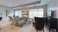 This single-floor, two-bedroom, two-bathroom residence at Bishops offers a thoughtfully designed layout that balances comfort and modern style. Light wood flooring runs throughout the living areas, contributing to a bright, cohesive aesthetic.

The living room features a tray ceiling detail, recessed lighting, and horizontal windows that invite natural light while maintaining privacy. The space comfortably accommodates a sectional sofa and accent seating, with a dining area visible nearby.

The kitchen is a standout feature, showcasing two-tone cabinetry with rich wood lower cabinets and white upper cabinets, dark granite countertops, a subway tile backsplash, stainless steel appliances, and a center island with a white quartz surface and built-in wine storage.

Both bedrooms are serene and well-proportioned, featuring light walls, wood-look flooring, and windows with privacy blinds. One bedroom includes a walk-in closet with built-in shelving and rail systems. The primary bathroom offers a frameless glass walk-in shower with floor-to-ceiling white tile and mosaic tile flooring. The second bathroom features a tub-shower combination with a wood-toned vanity and quartz countertop.
